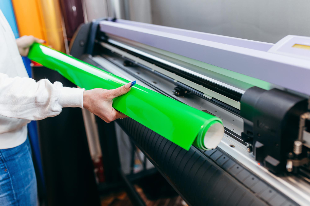 Cutting plotter: a professional using the equipment to cut vinyl material.