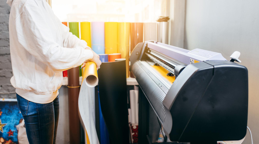 A professional using a cutting plotter to cut vinyl material.