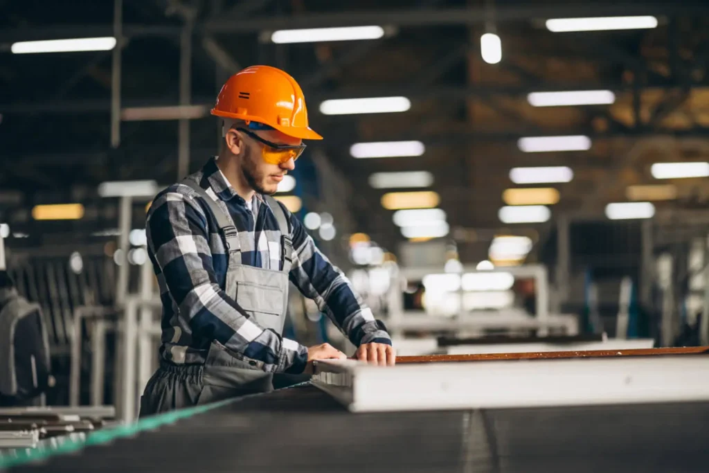 Industria colombiana: un hombre con un casco de seguridad naranja fabricando un objeto cuadrado.