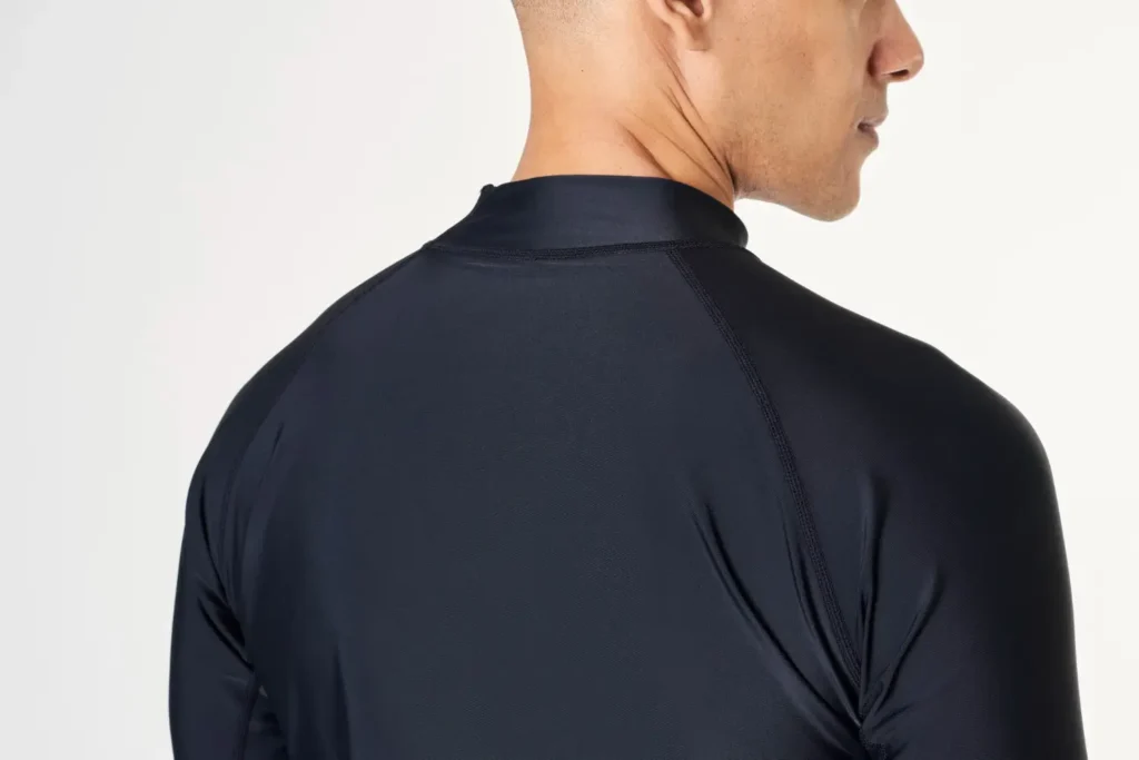 Homem de costas usando uma blusa preta de tecido tecnológico e respirável, um dos tipos de roupas ergonômicas.
