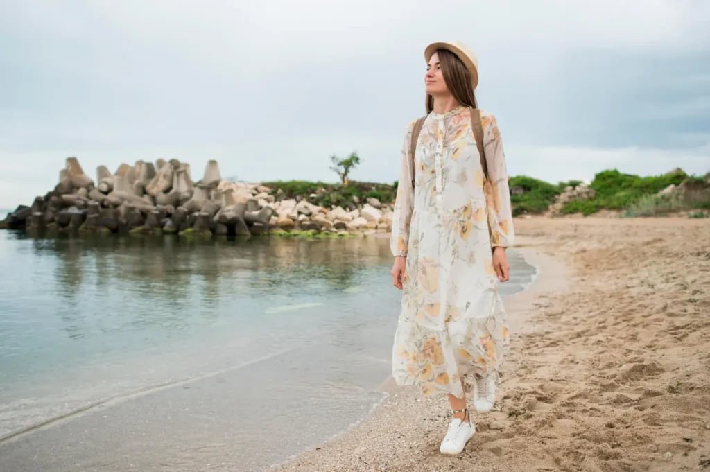 Tipos de estampados: mujer caminando en una playa con un vestido largo con estampado florar