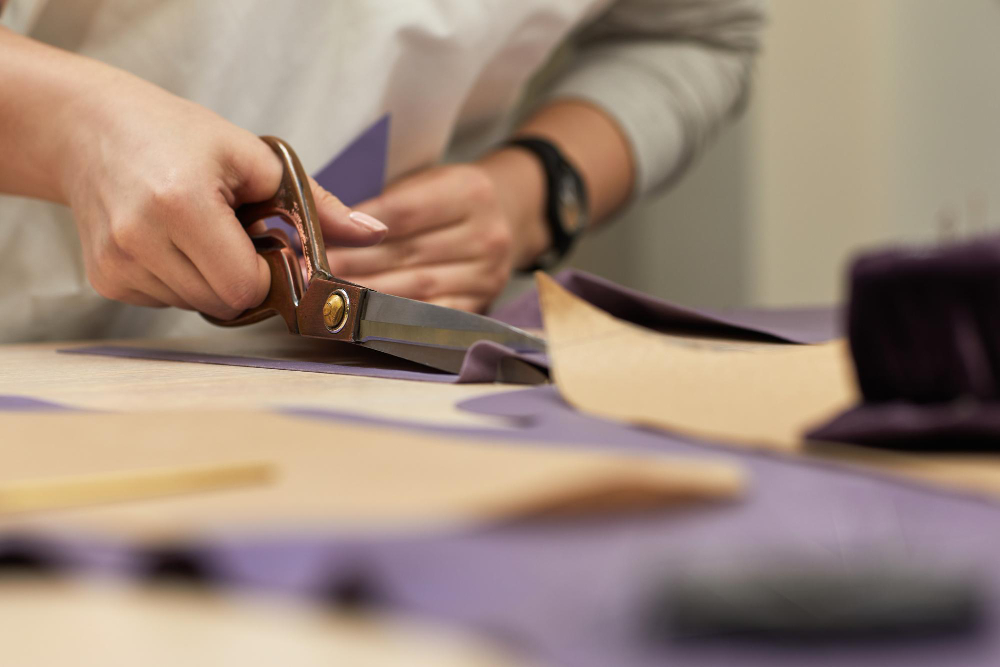 Clothing manufacturing: a fashion professional cutting fabric by hand.