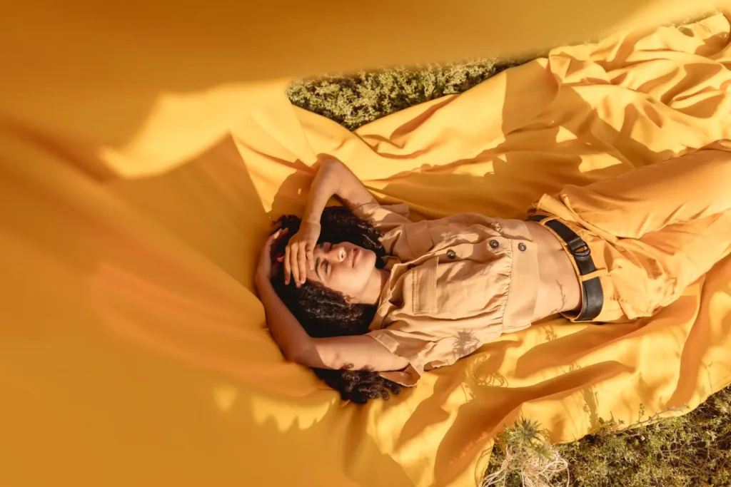 Mulher deitada em um tecido amarelo em um campo. Exemplos de empresas sustentáveis no Brasil.