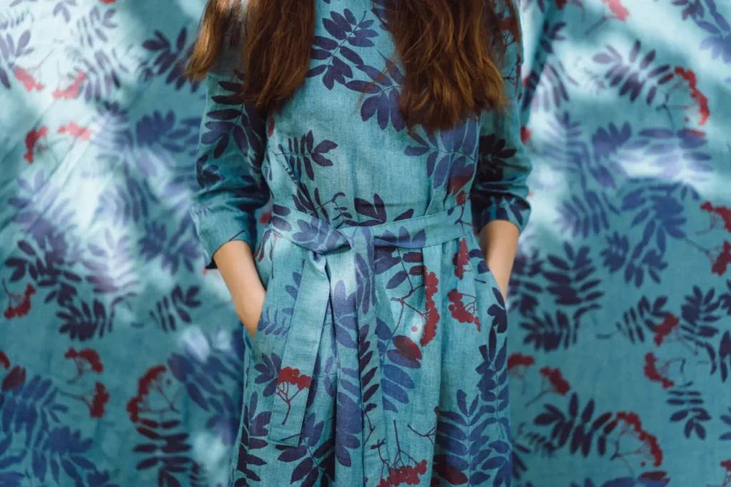 Estampado personalizado: mujer con vestido estampado azul con hojas en una pared con el mismo estampado