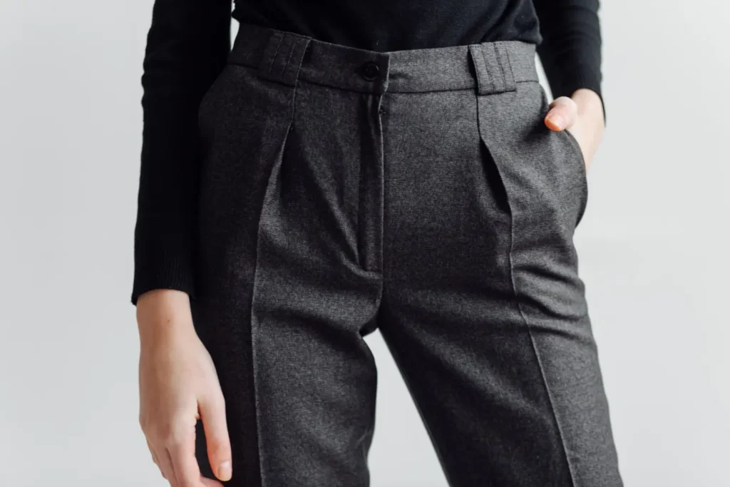 Cós com passador em uma calça de alfaiataria cinza.