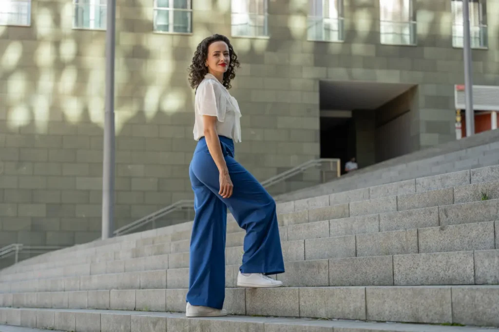 Dise&ntilde;ar pantalones: mujer subiendo escaleras vestida con un pantal&oacute;n azul