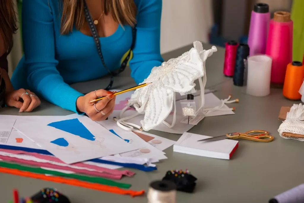 Estilista analisando tecidos e detalhes para fazer seu desenho t&eacute;cnico.
