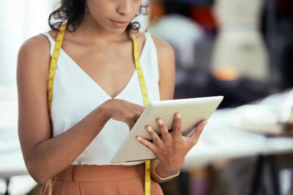 derechos de autor: mujer mirando un tablet en un taller de ropas