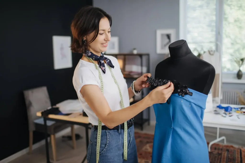 diseñadores de moda mexicanos: estilista arreglando un vestido azul en un maniquí