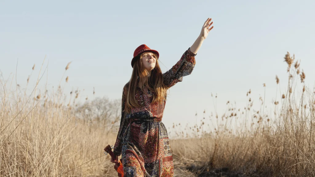 Donna in stile hippie, uno dei movimenti della storia della moda, che cammina tra il fogliame.