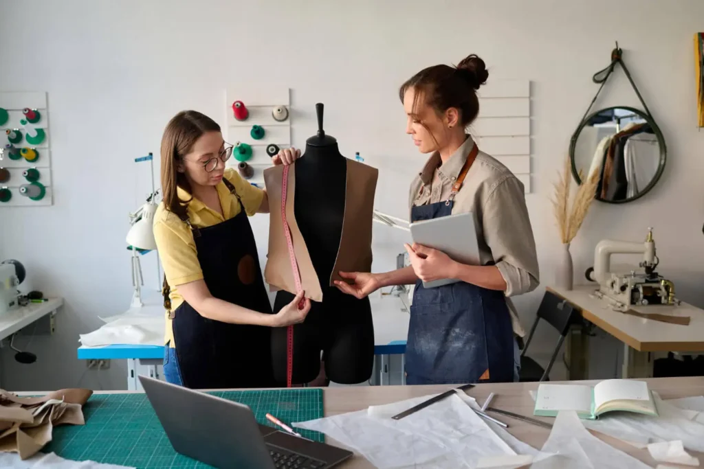 ia para crear ropa: mujeres con una computadora en un taller de prendas