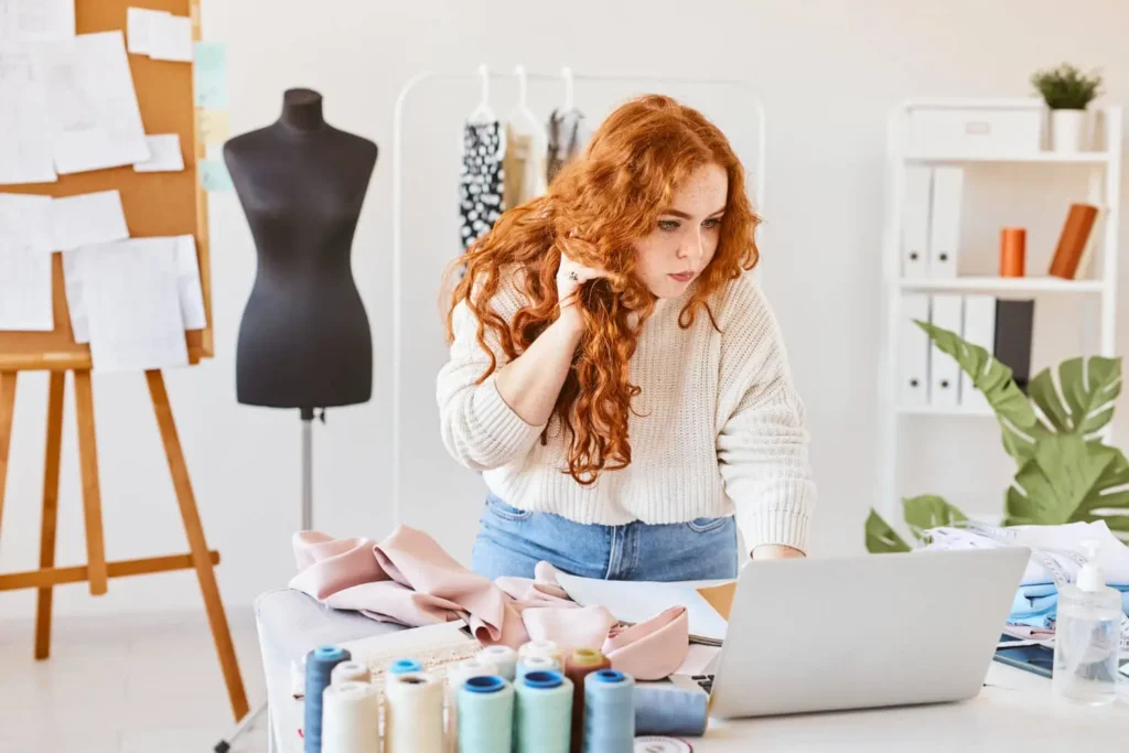ia para crear ropa: mujer con una computadora en un taller de prendas