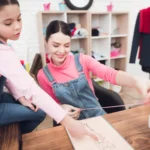 La proprietaria di un atelier di moda per bambini e una bambina che controlla le misure di un tessuto.