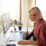 A woman with pink hair looking at a computer screen with charts, calculating time-to-market.